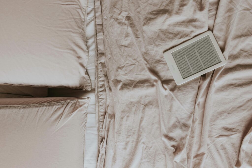 Top view of a cozy bed with an ebook reader on soft sheets, perfect for relaxed reading enthusiasts.